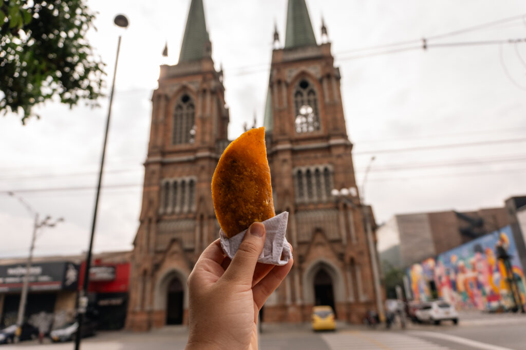 Empanada típica colombiana con la iglesia Nuestra Señora del Perpetuo Socorro en el barrio Perpetuo Socorro de Medellín, Antioquia