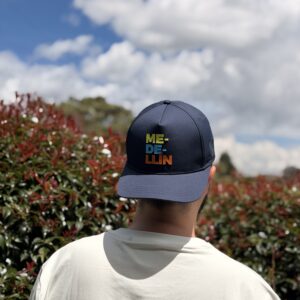 Gorra unisex Medellín azul oscuro con diseño tipográfico multicolor estilo urbano.